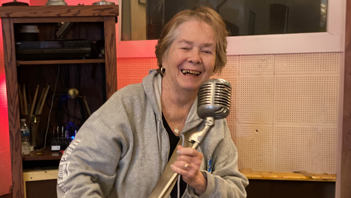 Person holding a vintage-style microphone in a recording studio.